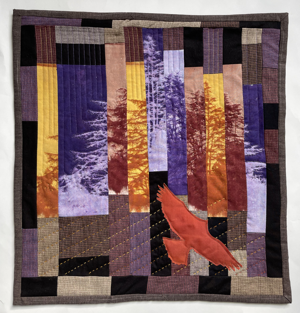 pieced quilt with an eagle flying up through strips of trees