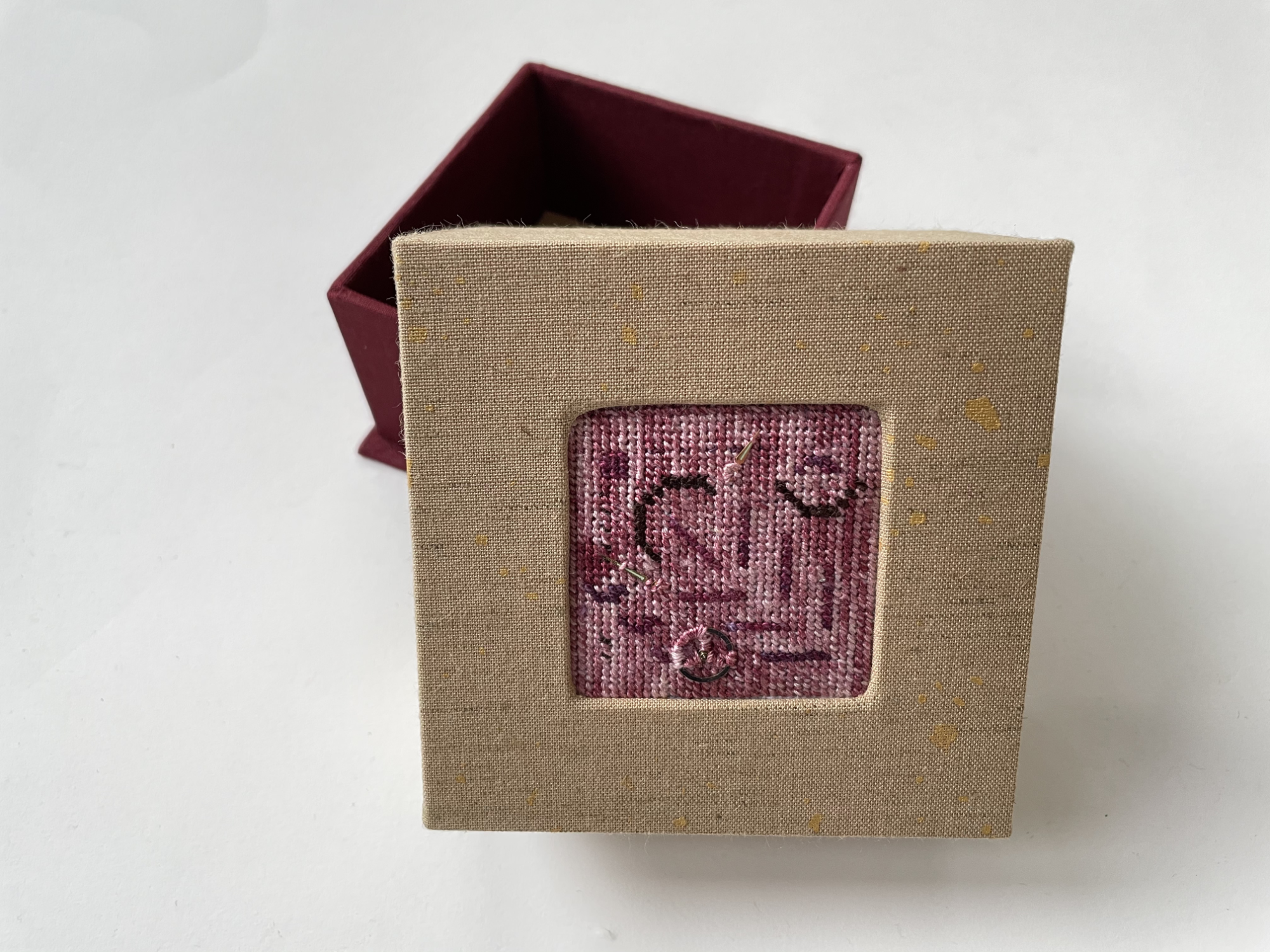 a box with an inset abstract needlepoint with watch hands and gear