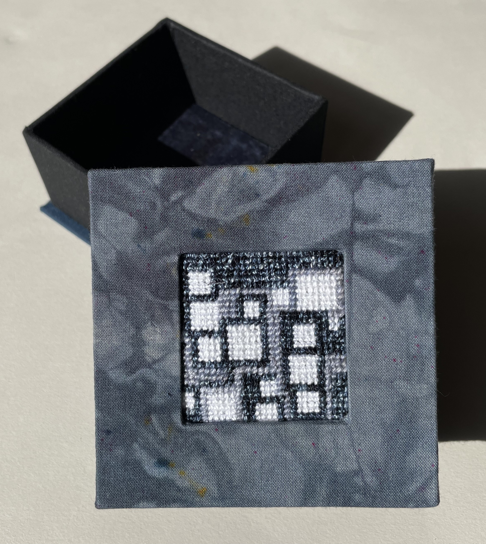 a box with an inset abstract needlepoint of small squares