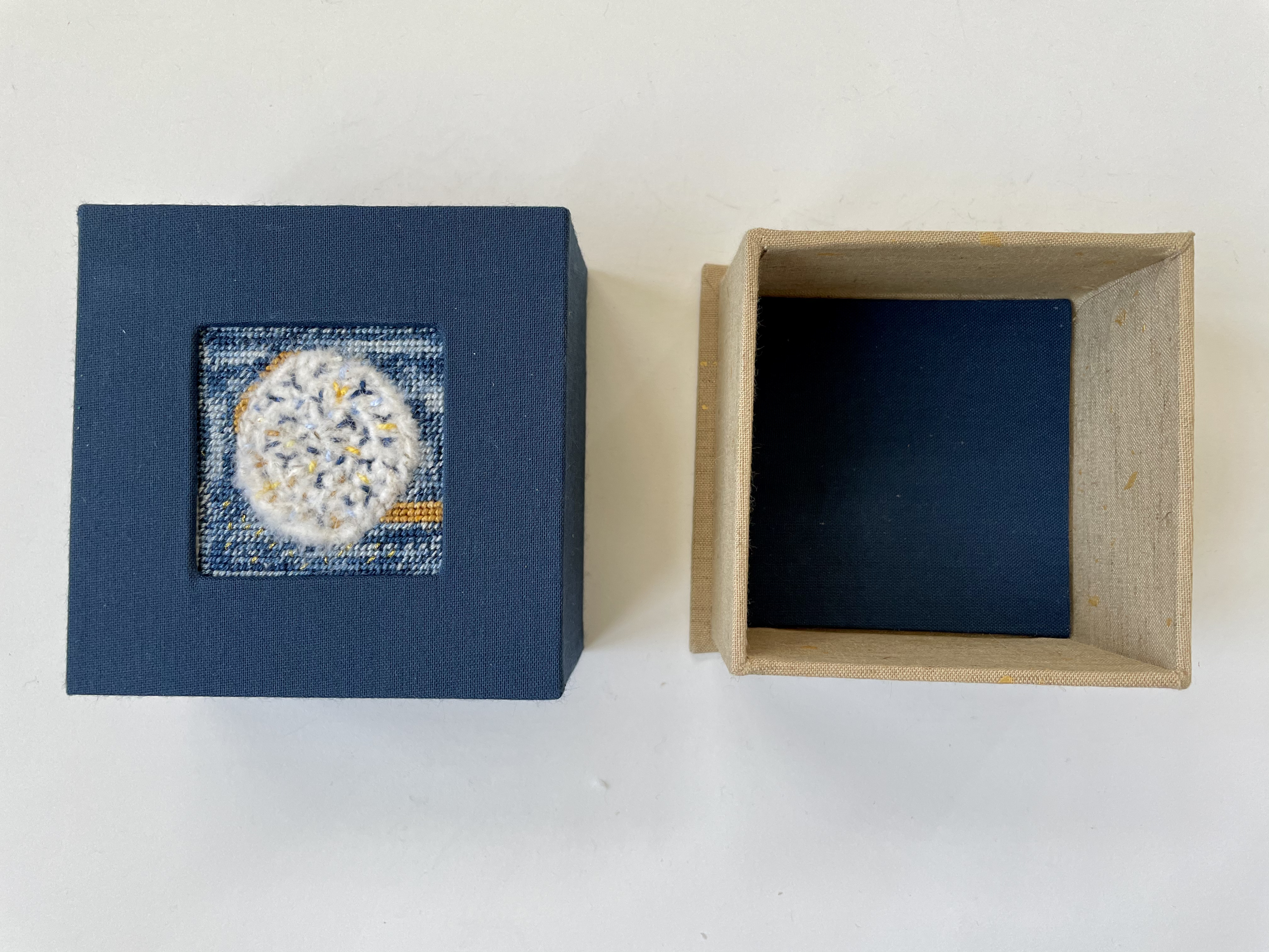 a box with an inset needlepoint and fuzzy circle